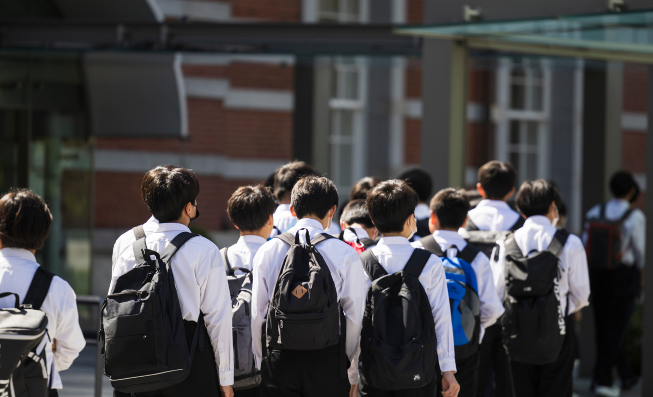 リュックを背負って学校施設へ向かう学生の集団