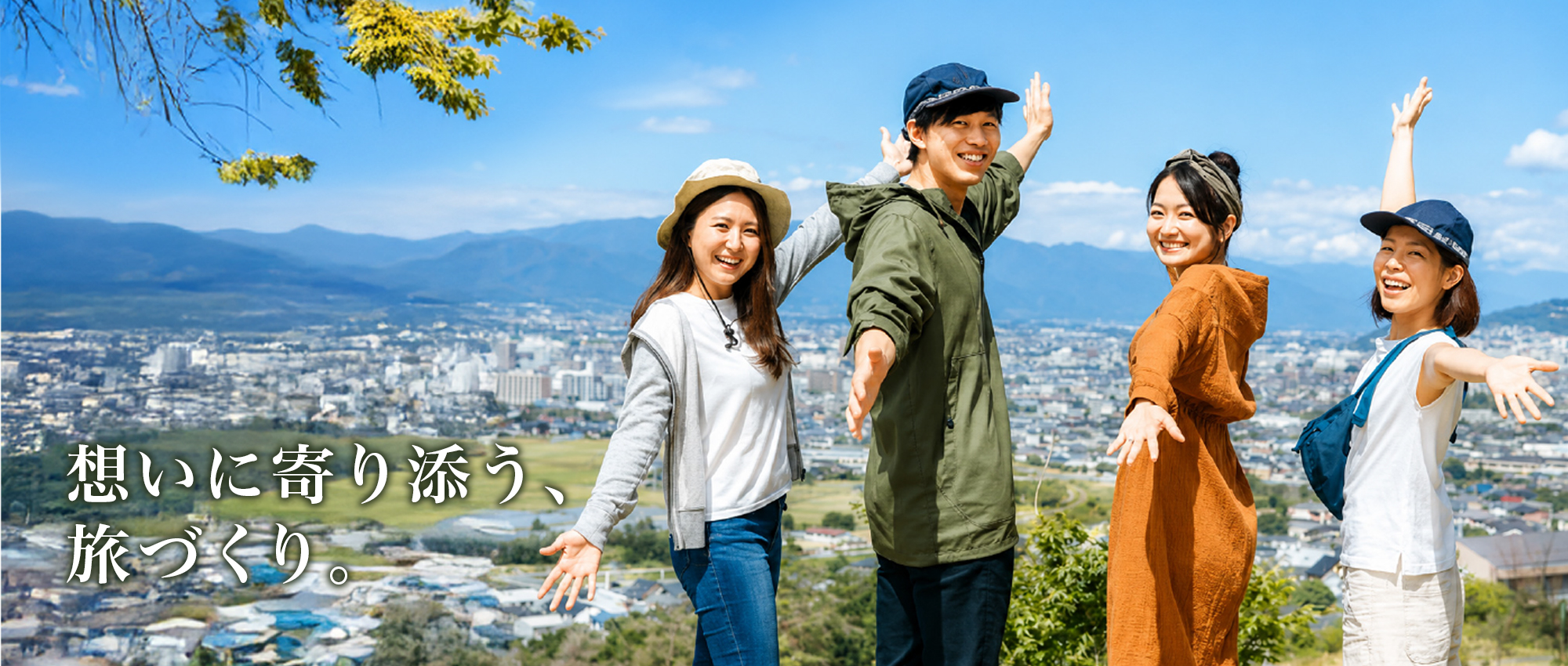 山と街並みを背景に旅行を楽しむ4人の参加者